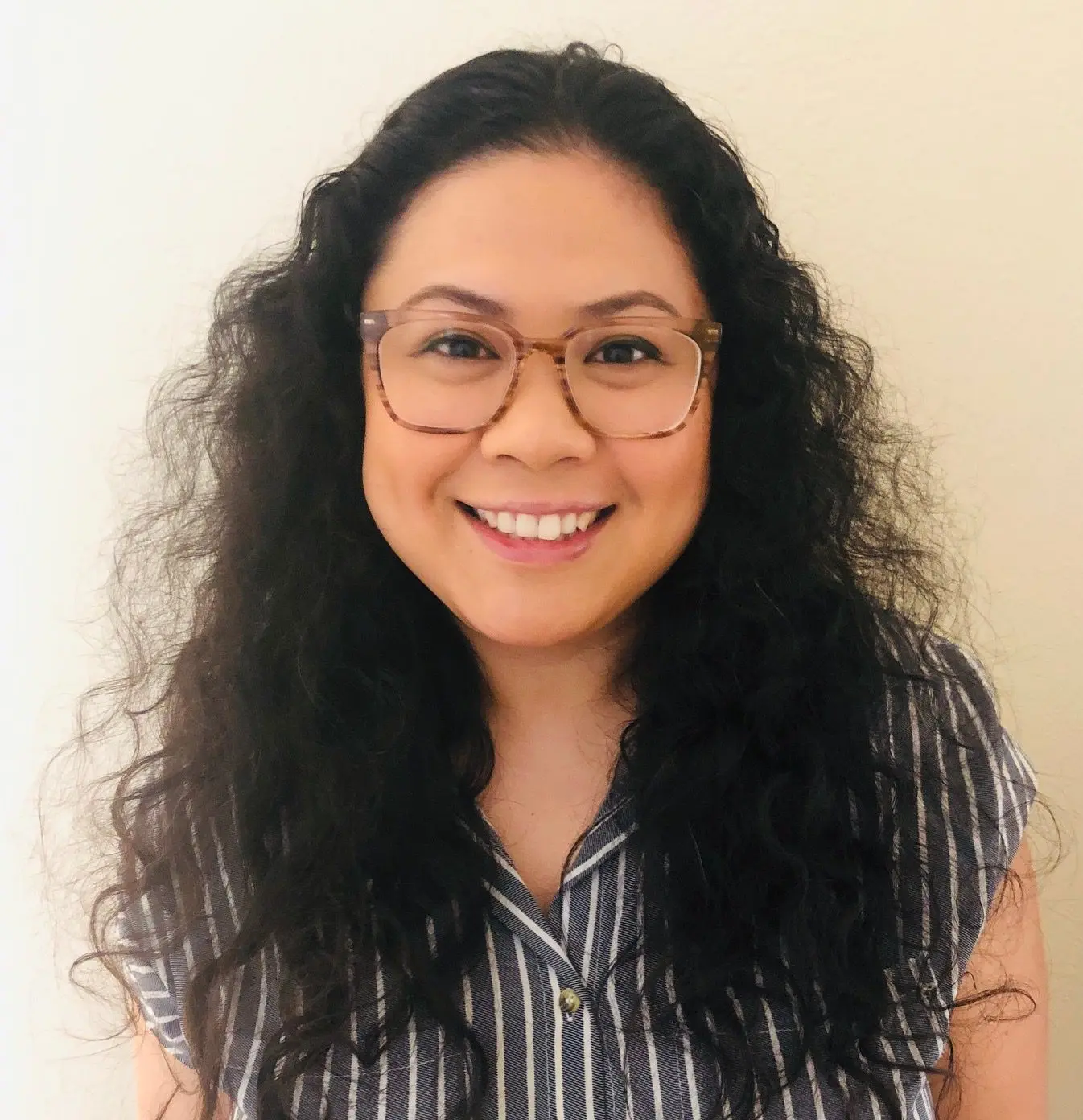 A woman with long black hair wearing glasses.