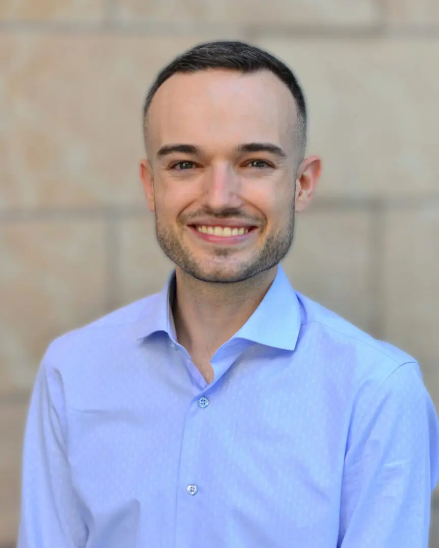 A man in blue shirt smiling for the camera.