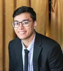 Smiling person in glasses and suit.