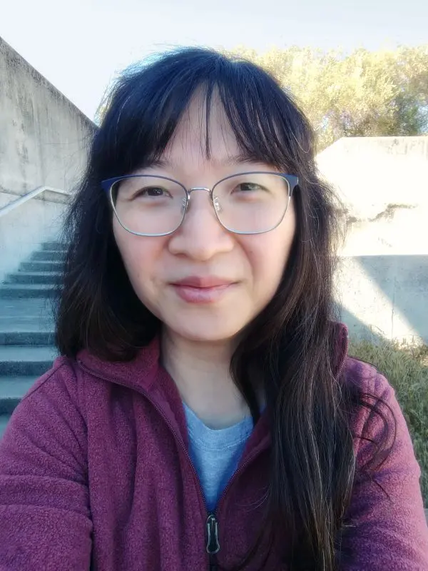 Woman with glasses, dark hair, maroon jacket.