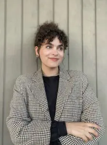 Woman in houndstooth jacket, smiling.