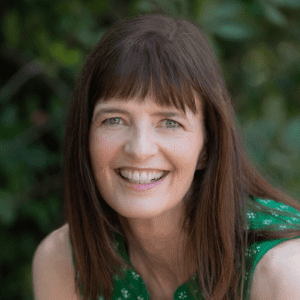 Smiling woman with brown hair in green dress.