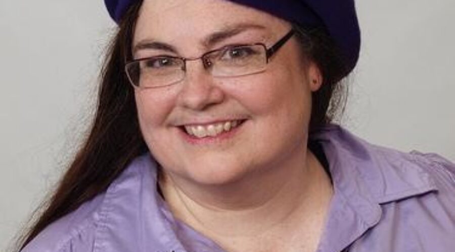 A woman wearing glasses and purple shirt with a hat.