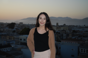 A woman standing on top of a building in front of the city.