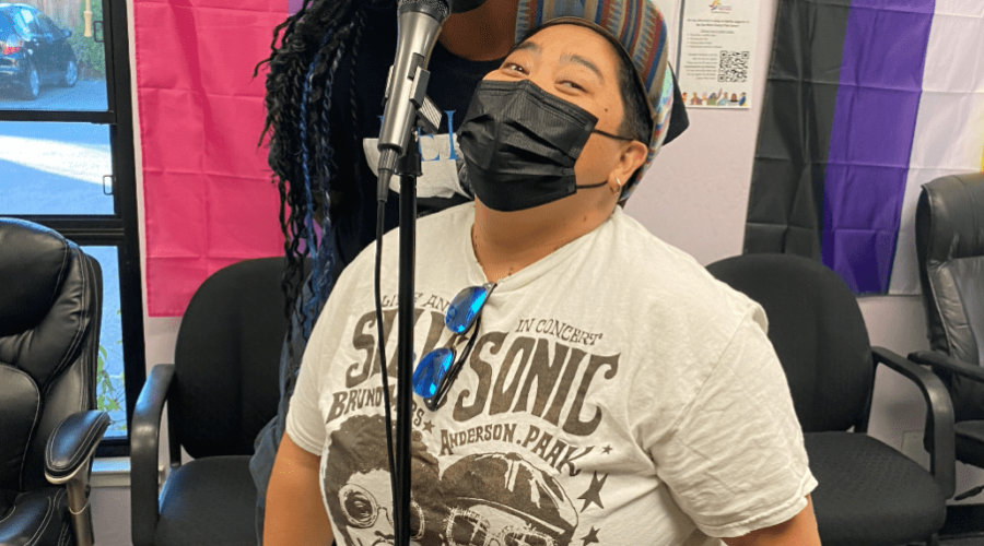 Two masked people singing into a microphone.